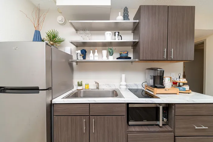 Contemporary kitchen with sleek modern cabinets, a stainless steel refrigerator, and stylish open shelving, offering functionality and elegance.