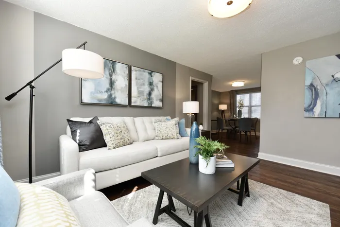 Modern and inviting living room with sleek decor, plush seating, and stylish artwork, opening to a cozy dining area.