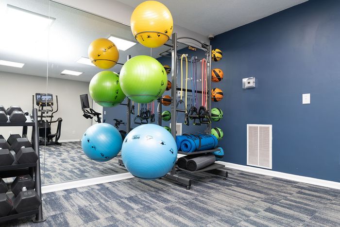 Vibrant fitness room featuring colorful exercise balls, weights, and versatile workout equipment in a modern setting.