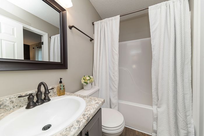 Modern bathroom with elegant granite countertop, sleek sink, and polished fixtures, complemented by a chic shower curtain and subtle floral decor.