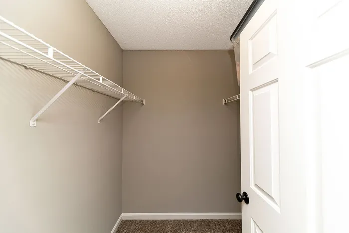 Spacious walk-in closet with sleek white wire shelving, perfect for ample storage and organization.
