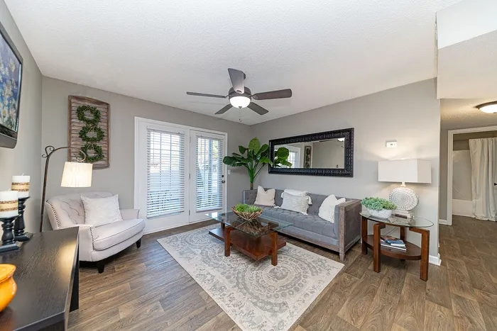 Elegant living room featuring chic decor, plush seating, large mirror, and natural light through French doors.