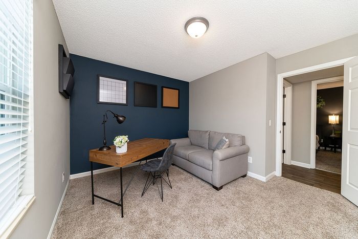 Bright home office with a cozy gray sofa, sleek wooden desk, and modern wall art, perfect for productivity and relaxation.