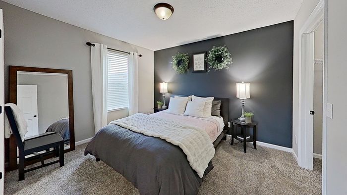 Inviting bedroom with plush bedding, stylish dark accent wall, and elegant decor in a serene setting.