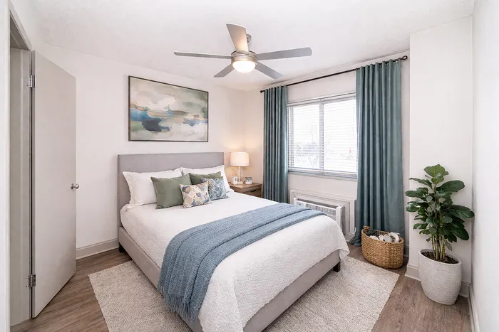 Elegant bedroom featuring a cozy bed with stylish pillows, calming blue curtains, and modern decor, perfect for relaxation.