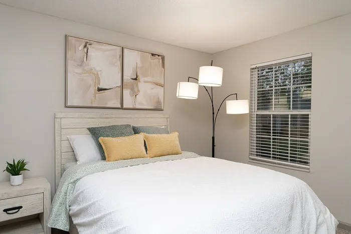 Inviting bedroom with modern artwork, cozy bedding, and elegant lighting for a serene atmosphere.