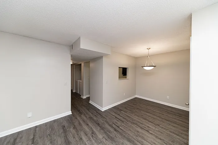 Elegant apartment interior showcasing a bright room with sleek wood flooring and a chic overhead light fixture.