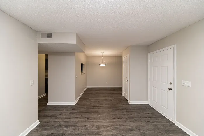 Modern apartment entryway with elegant dark wood flooring, inviting ambient lighting, and neutral-toned walls.