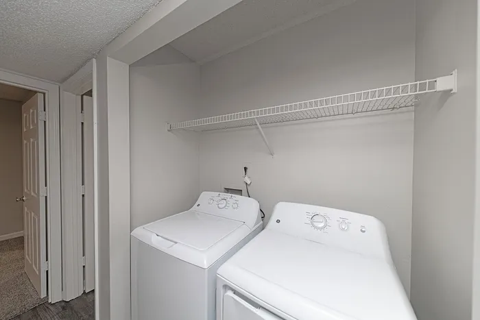 Modern laundry area with sleek washer and dryer, featuring convenient shelving in a bright, functional space.
