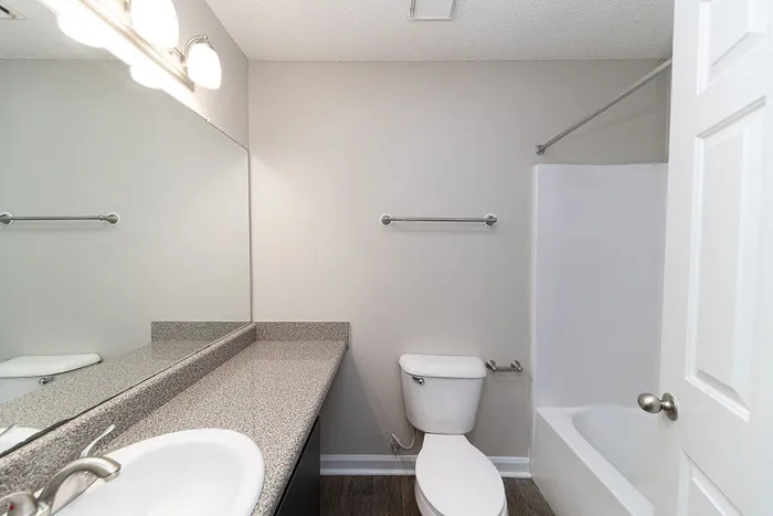 Modern bathroom with sleek granite countertop, large mirror, and bright lighting, offering a fresh and inviting atmosphere.