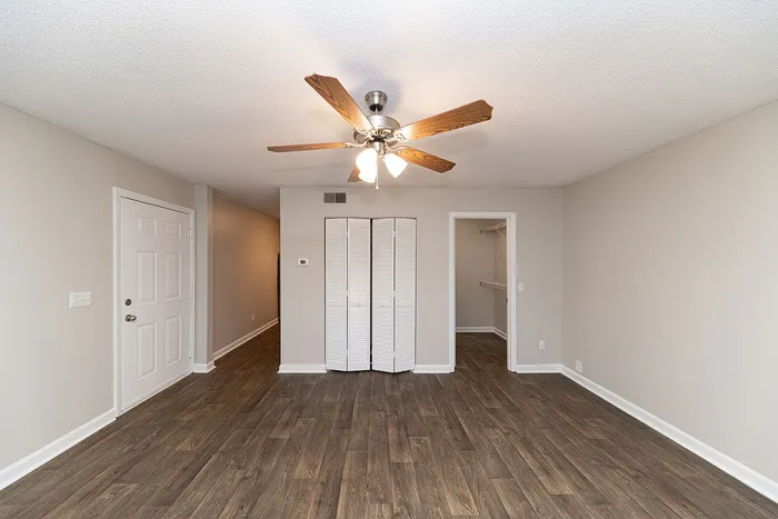 Bright living area with elegant hardwood floors, ceiling fan, and spacious closet space, ideal for stylish living.