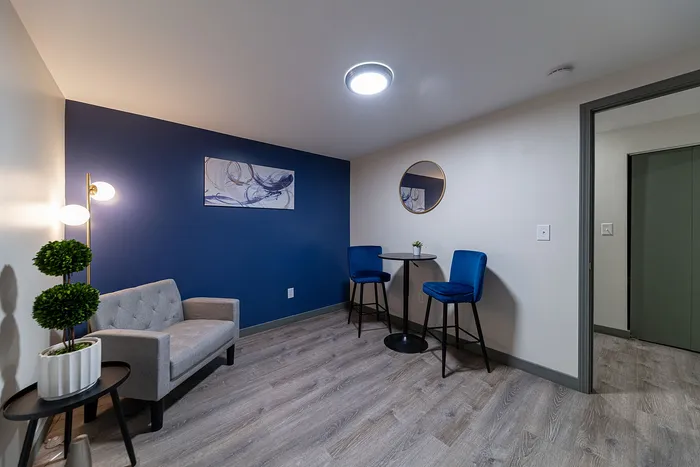 Cozy apartment nook with a stylish blue accent wall, plush gray sofa, chic bar table, and elegant decor.