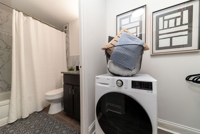 Modern apartment bathroom with elegant marble accents, featuring an in-unit washer and dryer for convenience.