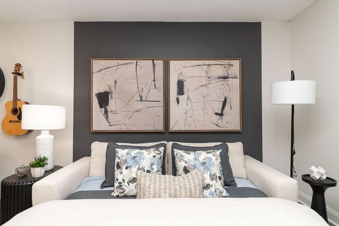 Elegant bedroom featuring modern abstract artwork, cozy pillows, and ambient lighting, creating a serene atmosphere.