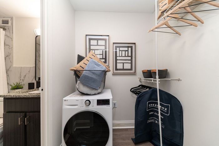 Modern laundry room featuring a sleek washing machine, stylish artwork, and convenient shelving, creating an organized and inviting space.