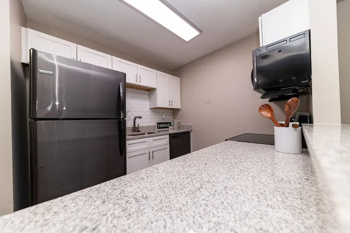 Modern kitchen with sleek stainless steel appliances, elegant white cabinetry, and polished granite countertops.