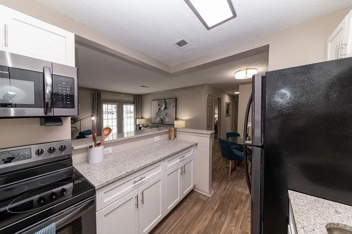 Bright, modern kitchen featuring sleek countertops, stainless steel appliances, and bar seating with view into the cozy living area and elegant dining space.