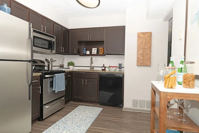 Modern kitchen with dark wood cabinets, stainless steel appliances, and elegant decor, offering a blend of style and functionality.