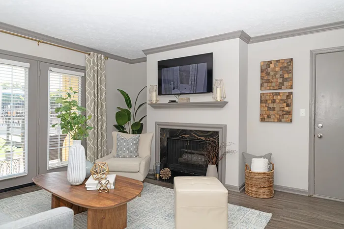 Inviting living room with modern decor, featuring a cozy fireplace, elegant furnishings, and abundant natural light from large windows.