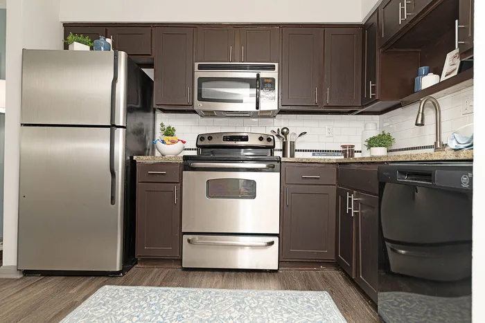 Sleek kitchen with stainless steel appliances, dark wood cabinets, and a modern design.