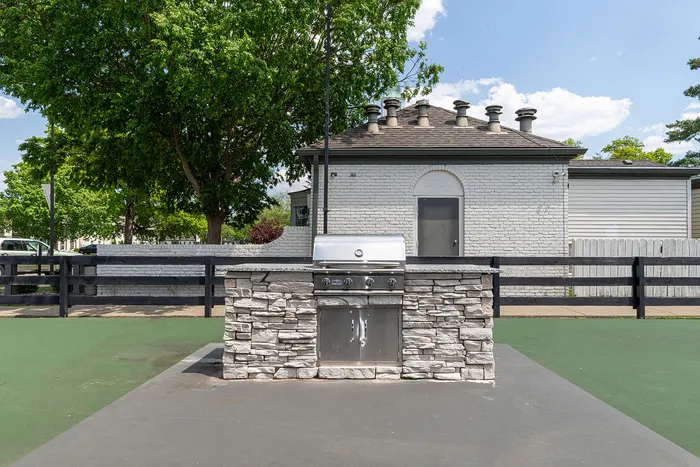 Charming outdoor grill station with a stone facade, perfect for entertaining under a sunny, blue sky.