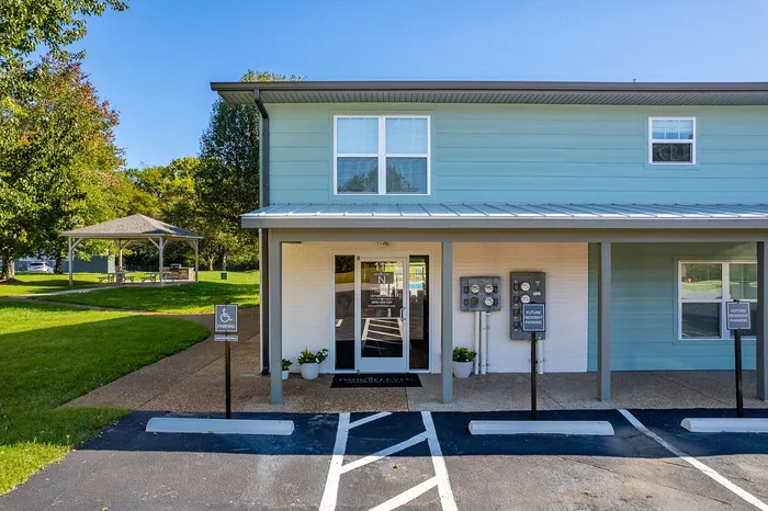 Charming apartment exterior with modern facade, accessible parking, and scenic green surroundings featuring a cozy gazebo.