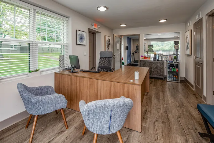 Modern office space with large windows, stylish wood desk, and cozy seating area, perfect for productivity and relaxation.