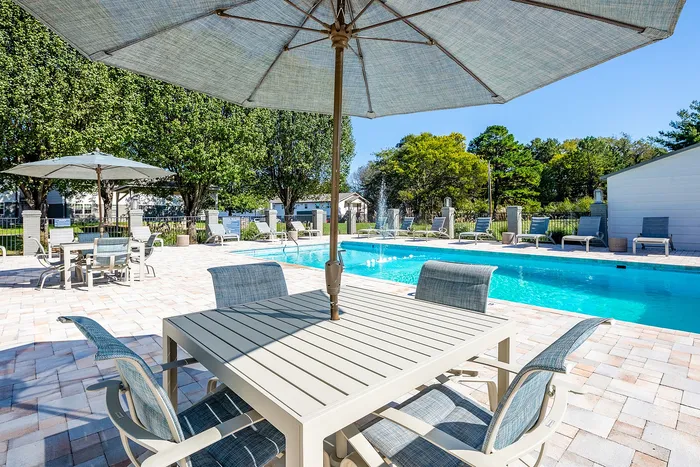 Luxurious outdoor pool area with elegant patio furniture and vibrant greenery, perfect for relaxation and entertaining.