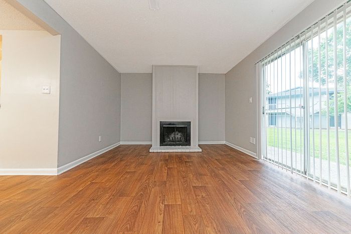 Inviting living room with elegant hardwood floors, cozy fireplace, and large sliding glass doors opening to a lush exterior.