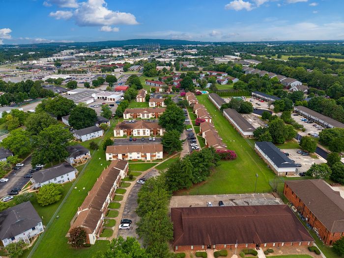Vibrant aerial view showcasing a well-planned apartment community with lush greenery, spacious layouts, and convenient parking.