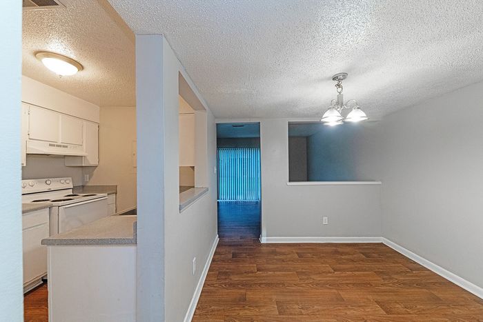 Bright open-plan living area with stylish wood flooring, featuring a cozy kitchen and ambient lighting.