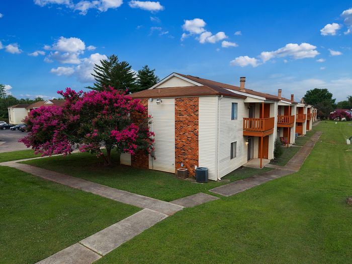 Charming apartment building with vibrant pink blossoms and lush greenery, perfect for serene living.