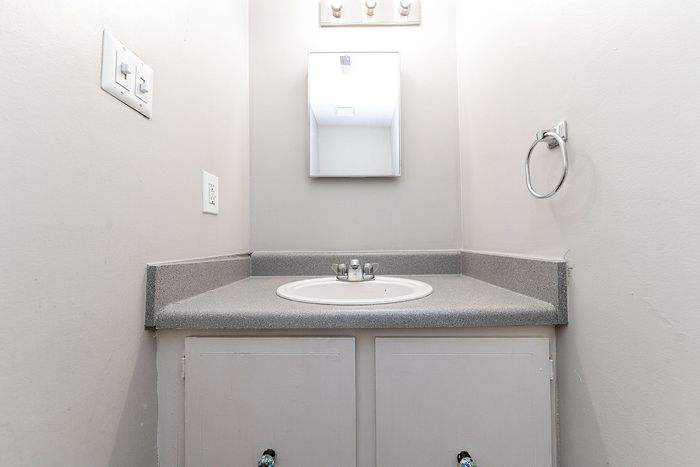 Chic compact bathroom vanity with smooth gray countertop and modern mirror lighting.