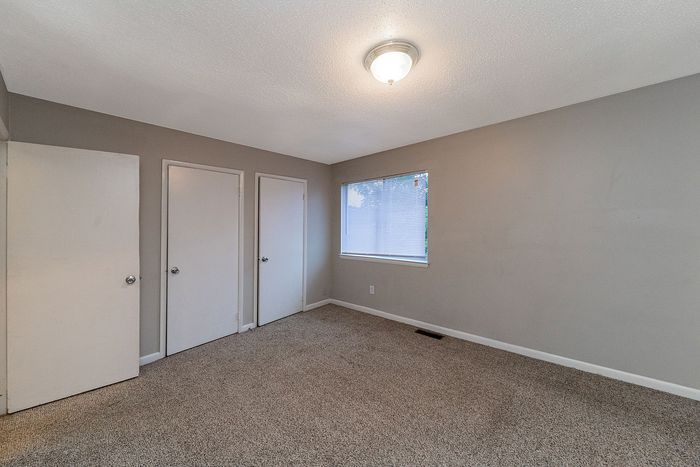 Spacious bedroom with neutral walls, cozy carpet flooring, and ample closet space.