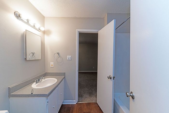 Bright and inviting bathroom featuring contemporary fixtures, elegant vanity with ample storage, and convenient access to an adjacent room.