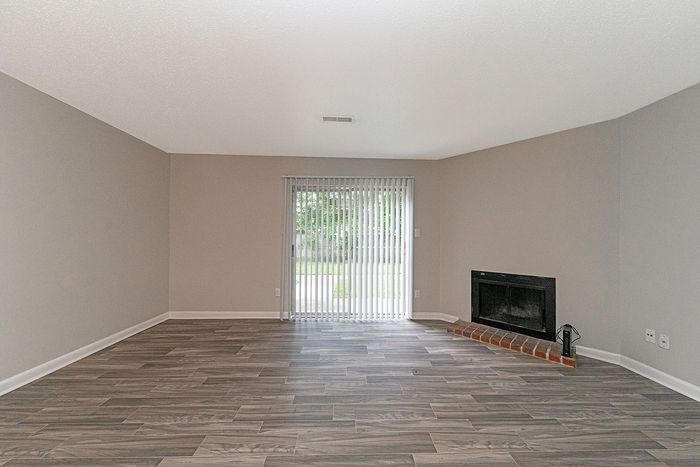 Elegant living room with sleek wood flooring, modern fireplace, and large sliding door with garden views.