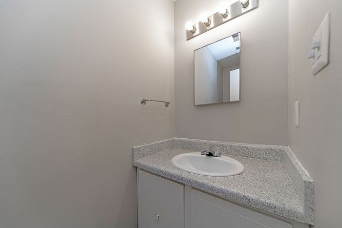Modern bathroom with sleek lighting, large mirror, and elegant granite countertop.