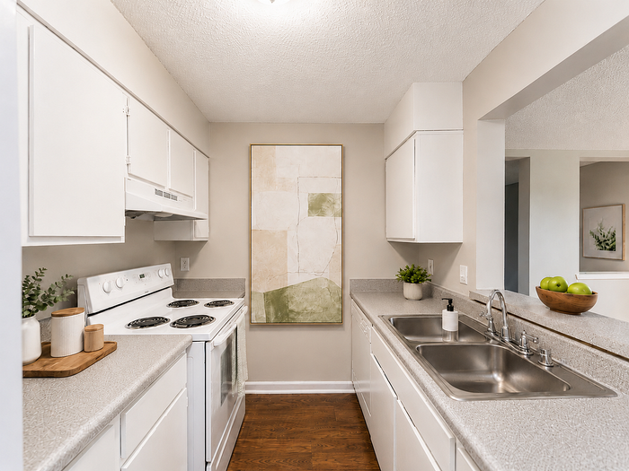 Modern kitchen with sleek white cabinetry, dual sink, and abundant counter space, accented by stylish decor and wooden flooring.