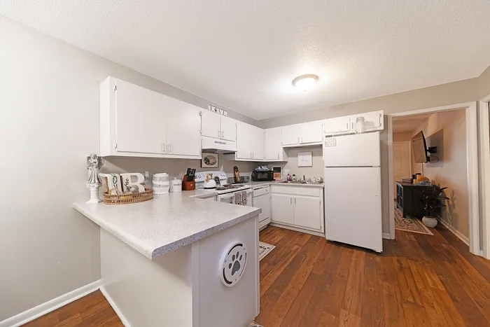 Charming kitchen with white cabinetry, modern appliances, and inviting hardwood floors, perfect for culinary enthusiasts.