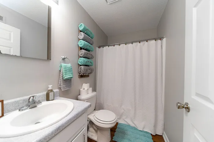 Inviting bathroom with elegant white countertop, neat towel arrangement, and calming aqua accents.