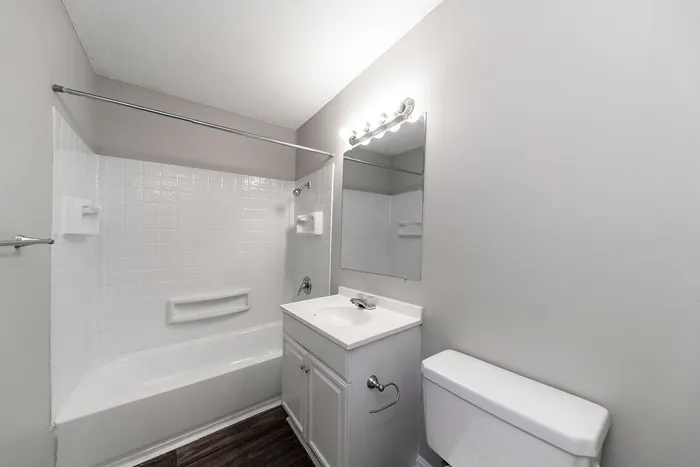 Modern bathroom with sleek white fixtures, inviting bathtub, and elegant vanity.