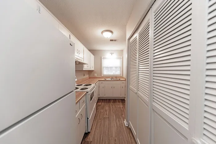 Charming galley kitchen with modern white cabinets, sleek countertops, and natural light ambiance.
