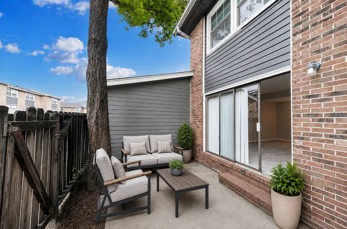 Charming outdoor patio with comfortable seating and lush greenery, perfect for relaxing in a stylish apartment setting.