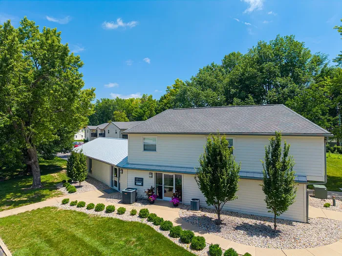 Charming two-story house with a manicured lawn, surrounded by lush greenery under a clear blue sky, perfect for family living.