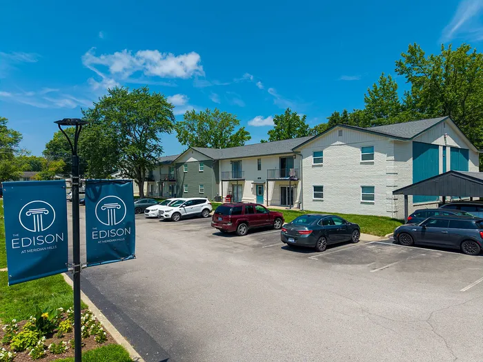 Charming apartment exterior at The Edison with ample parking and lush greenery, perfect for modern living.