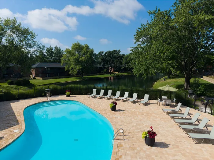 Luxurious outdoor pool area with elegant lounge chairs and vibrant greenery, surrounded by a serene landscape and gentle water view.