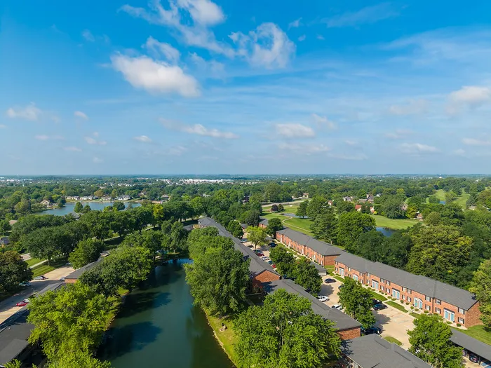 Scenic aerial view of charming apartment complex surrounded by lush greenery and tranquil waterways, offering a serene and picturesque living environment.