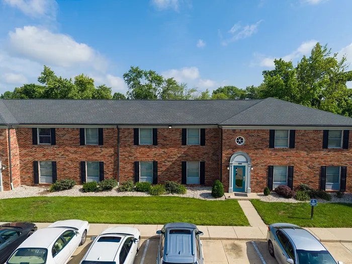Charming brick apartment building with lush green surroundings and convenient parking, offering a blend of classic style and modern amenities.