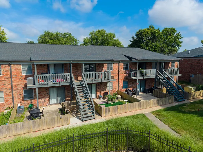 Charming brick apartment complex with private balconies and lush green surroundings, perfect for modern living.