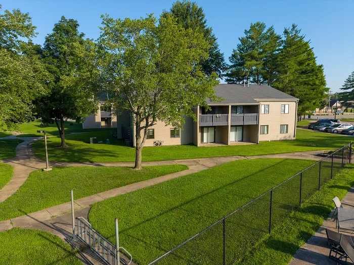 Charming apartment complex surrounded by lush green lawns and mature trees, featuring a bright, open exterior with balconies perfect for enjoying nature.